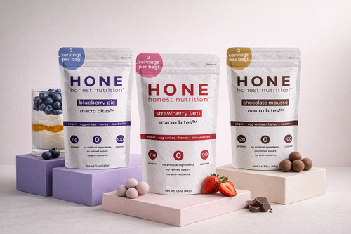 Three packages of honest nutrition macro bites on a light background with fruits and a glass.